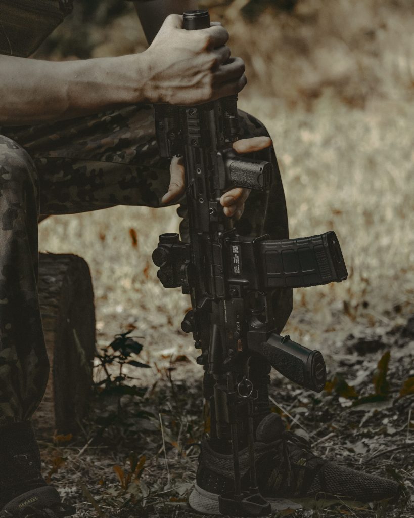 Man in camo trousers holding airsoft rifle