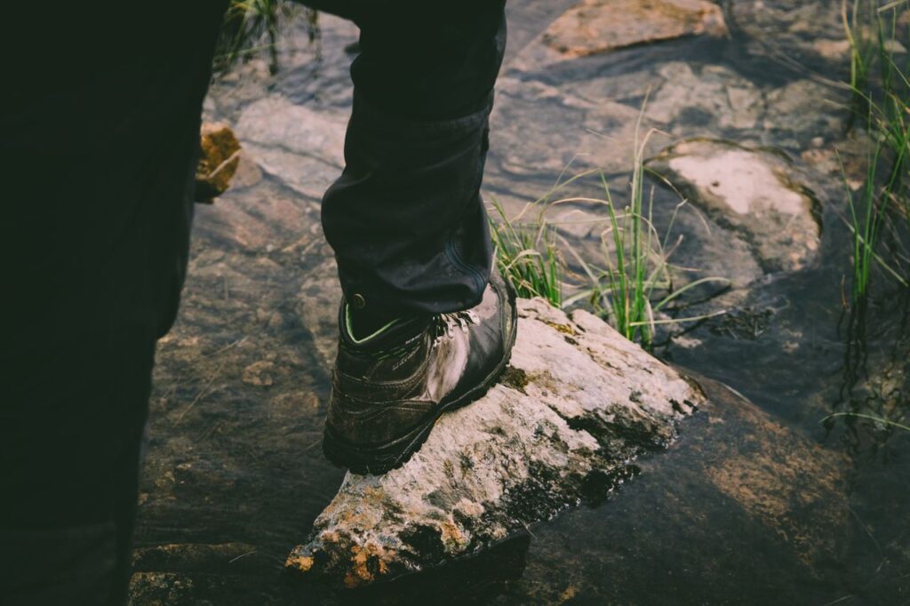 Man wearing outdoor boots and walking over stream
