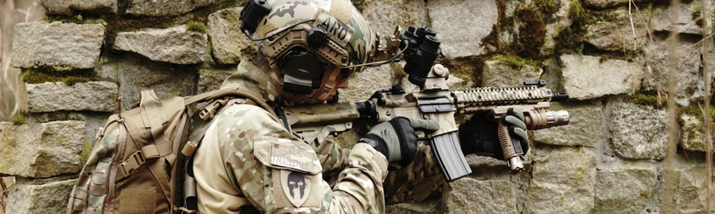 Airsoft player aiming gun by wall