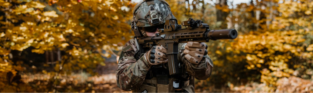 Airsoft player with gun in woods