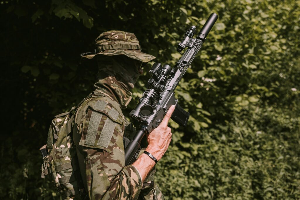An airsoft player in full camo in woodland