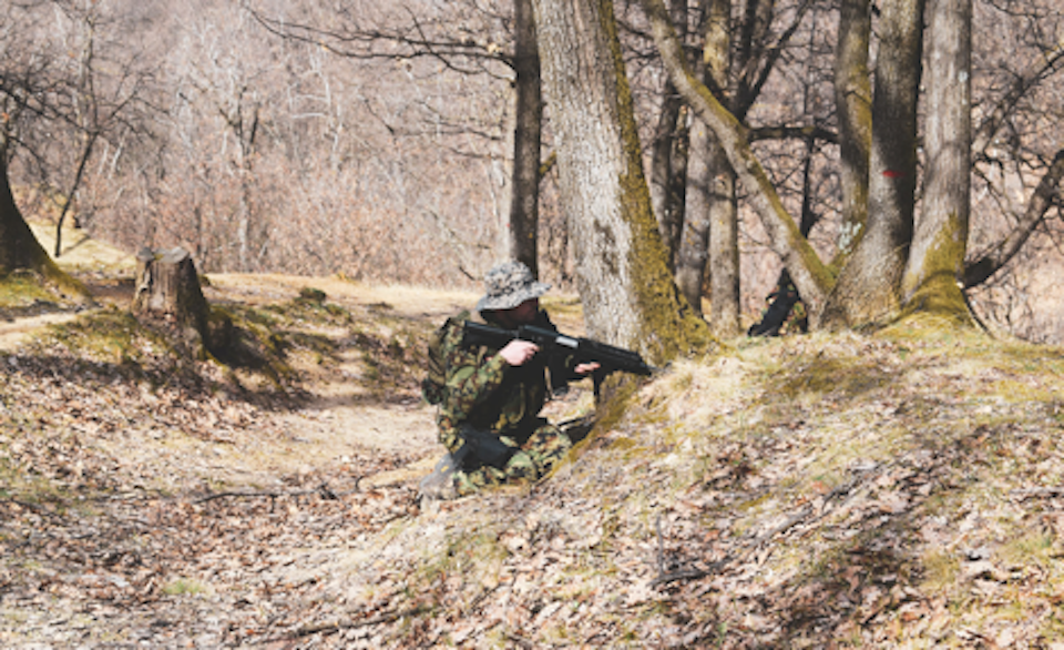 An airsoft player hiding behind a tree
