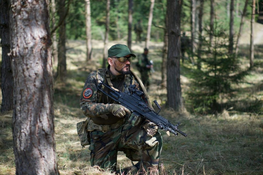 An airsofter crouched in the woods