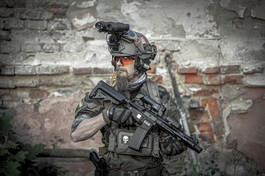 An airsoft player in full military loadout, holding a gun