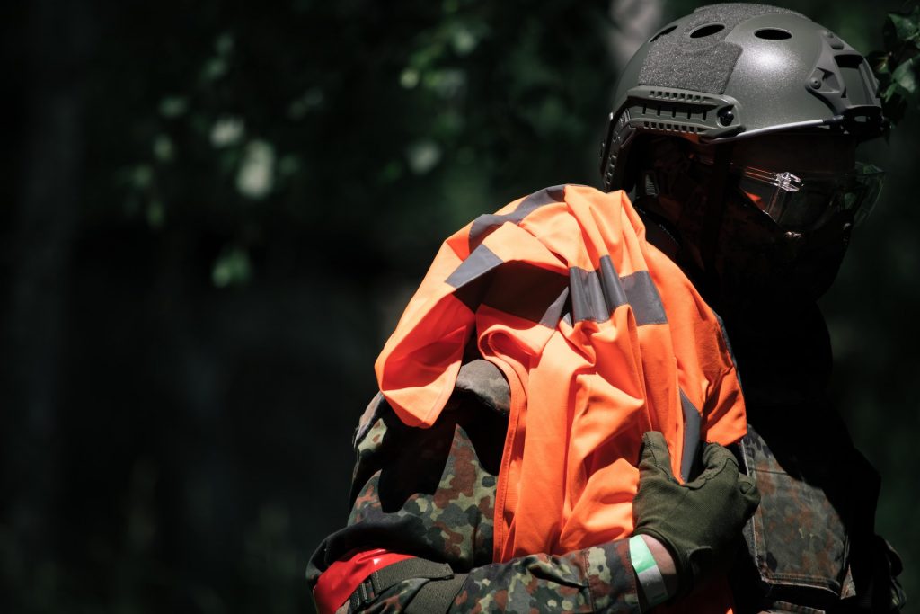 An airsoft player with helmet, goggles and high-visibility jacket