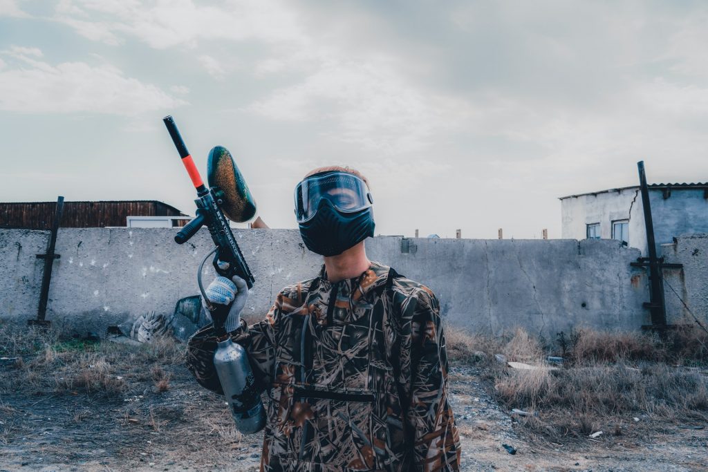 Some in a facemask with a paintball gun