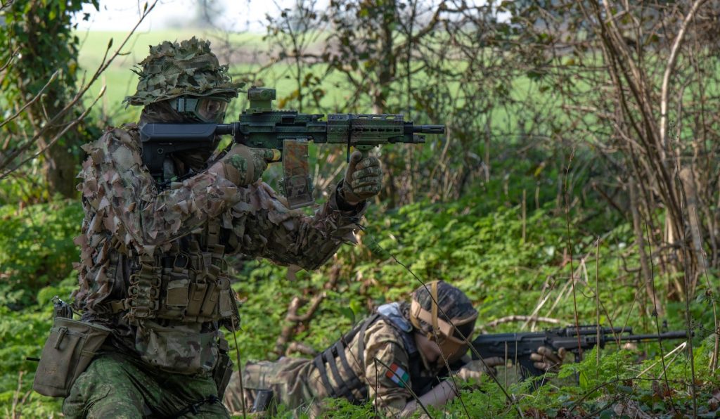 Two airsoft players aiming guns in the woods