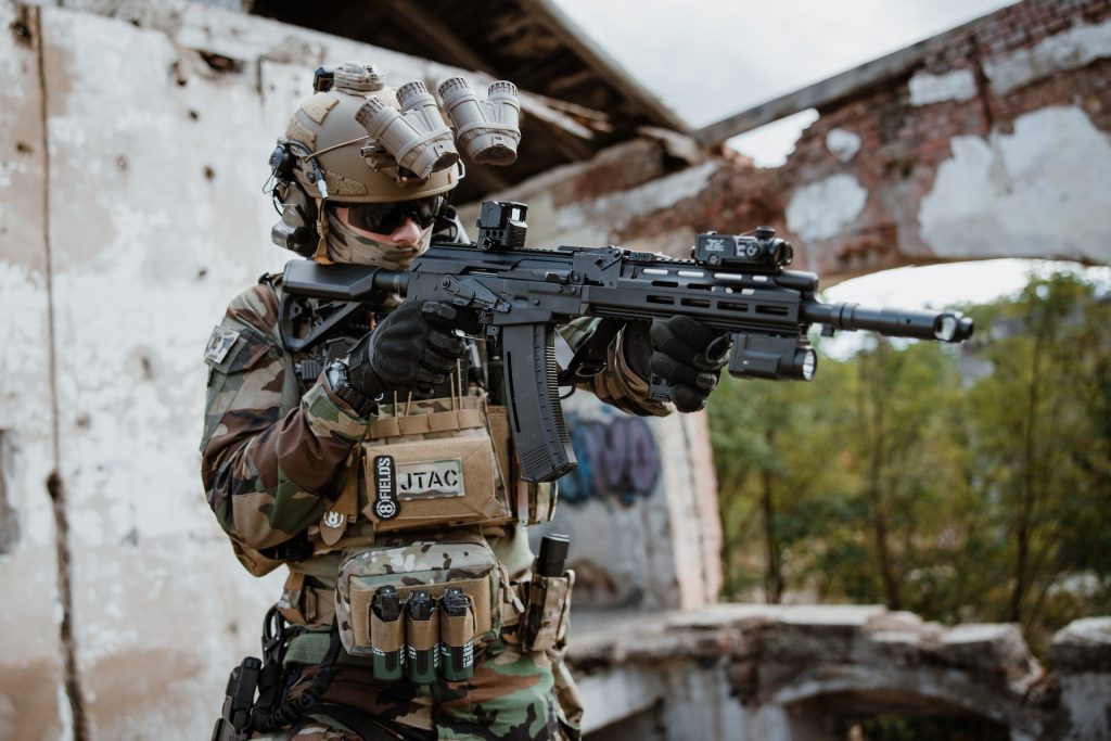 An airsoft player aiming a gun and wearing lots of tactical gear