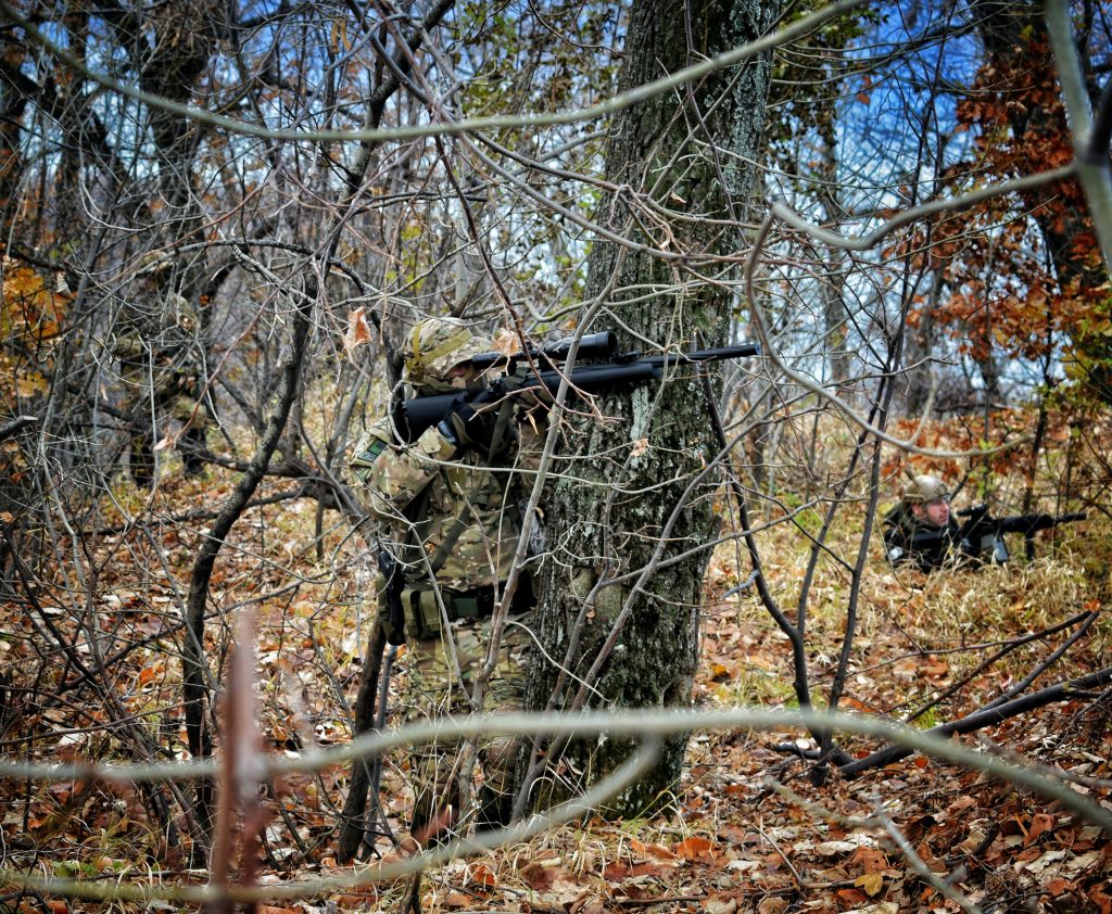 an airsoft player behind branches