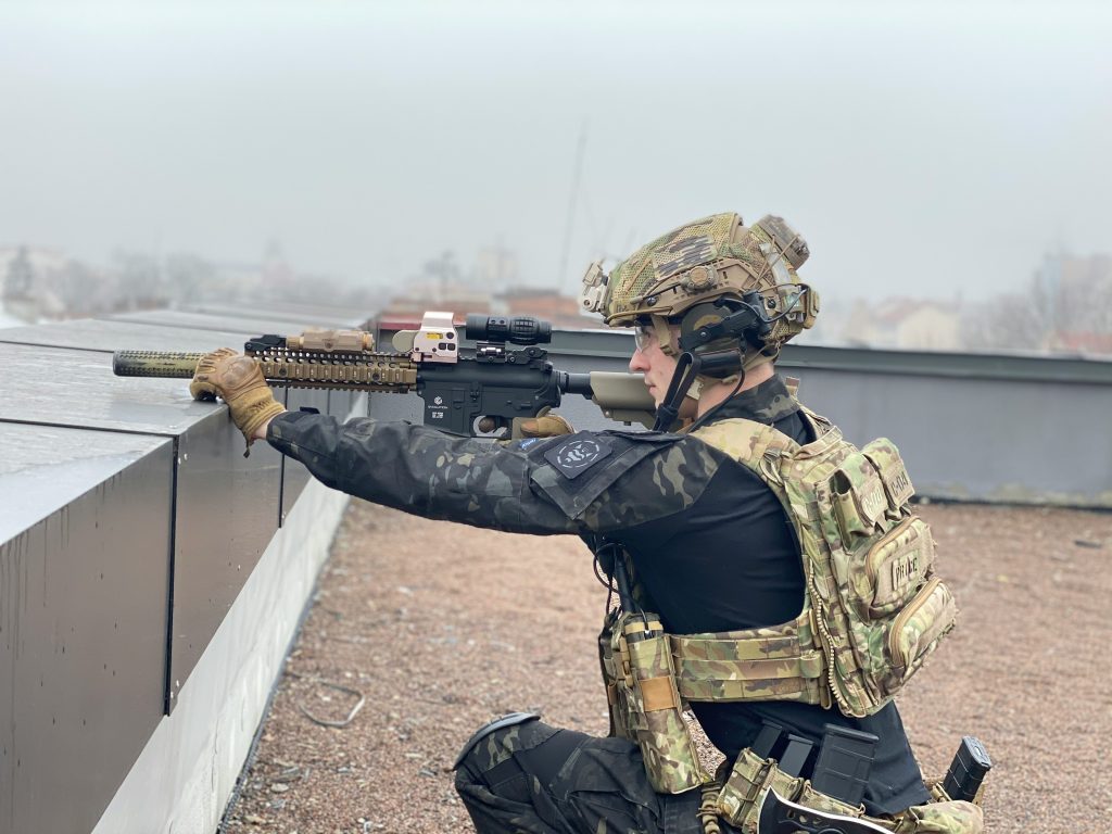 someone holding an airsoft gun dressed in camo