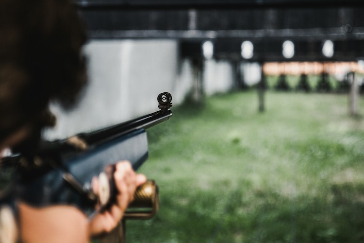 Someone aiming an air rifle at targets at a shooting range