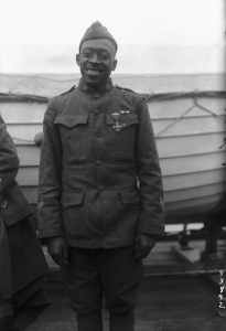 Pvt. Henry “Black Death” Johnson posing for a photo in front of a boat
