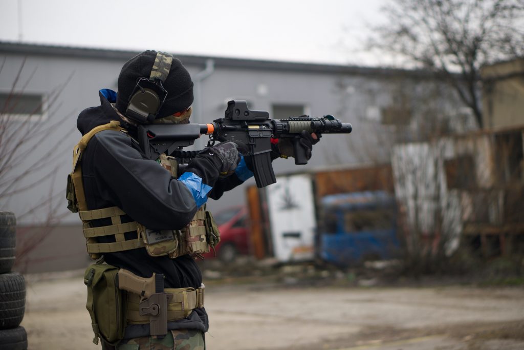 A person holding a gun aiming with a reflex sight