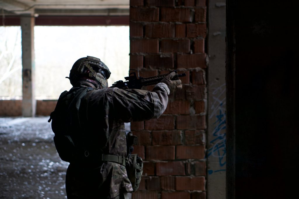 Person playing airsoft wearing camouflage, helmet and full mask