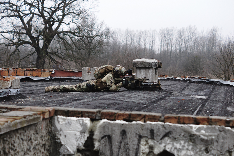 Person with rifle laying on roof
