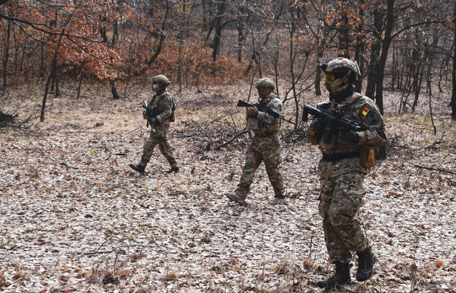 Three soldiers walking through woodland