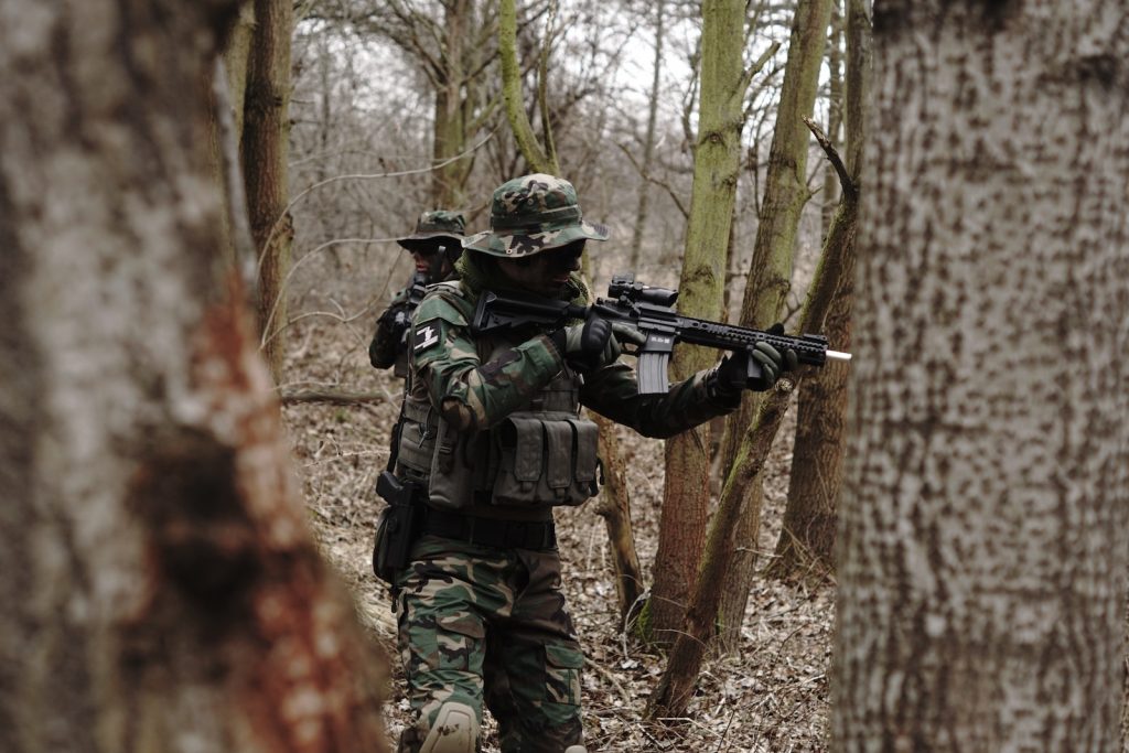 Person walking in woods with airsoft rifle